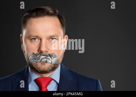 Uomo maturo con bocca tappezzata su sfondo grigio. Censura del discorso Foto Stock