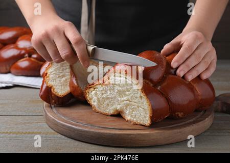 Donna che taglia pane fatto in casa intrecciato a tavola di legno, primo piano. Challah per Shabbat Foto Stock