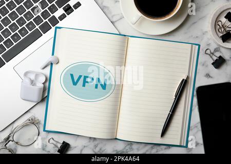 Notebook con acronimo VPN su tavolo in marmo bianco, piatto. Connessione di rete protetta Foto Stock