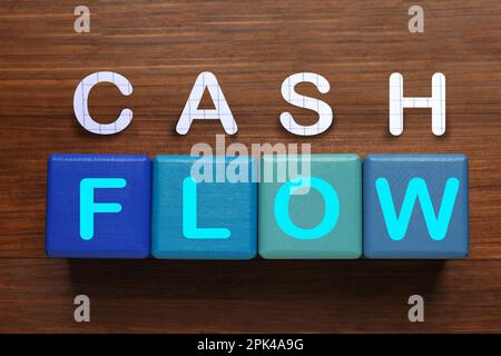 Frase flusso di cassa fatto con lettere e cubi blu su sfondo di legno, piatto Foto Stock