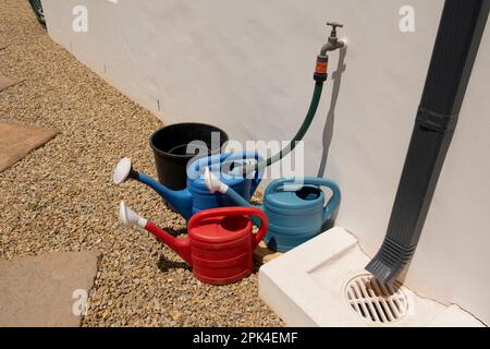 Langebaan, costa occidentale, Sudafrica. 2023. Le lattine di irrigazione vengono riempite da un tubo flessibile e picchiettare su un percorso da giardino. Foto Stock