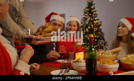 La famiglia festeggia il Natale insieme mangiando cibo speciale nella sala da pranzo Foto Stock