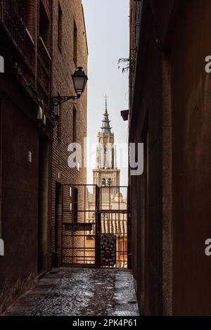 Toledo, Spagna - 19 febbraio 2023: Vista della torre della cattedrale di Toledo attraverso uno stretto vicolo della città medievale. Foto Stock