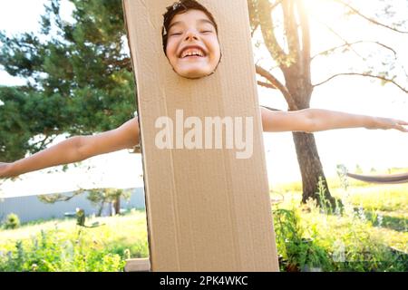 Il bambino sta ballando divertente e imbrogliando intorno in un costume della scatola - taglio rotondo per il viso e le mani. Spostandosi in una nuova casa, giochi per bambini da Imprised Foto Stock