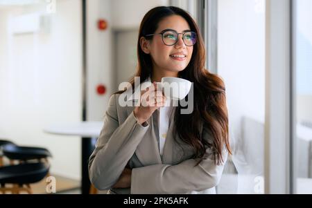 Sorridente ritratto di bella donna d'affari con una tazza di caffè in ufficio Foto Stock