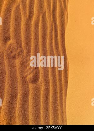 Stampa di scarpe su una duna di sabbia nel deserto del Sahara, Merzouga. Grani di sabbia che formano piccole onde sulle dune. Tramonto. Marocco Foto Stock