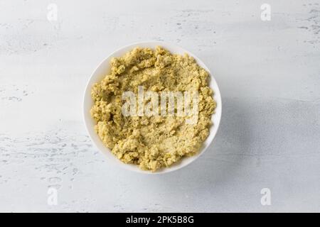 Ciotola bianca con lenticchie verdi macinate e bagnate su sfondo azzurro, vista dall'alto. Cucinare cibi vegani sani Foto Stock