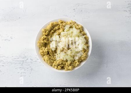 Ciotola bianca con lenticchie verdi macinate, cipolle e spezie su sfondo azzurro, vista dall'alto. Cucina sana vegan cibo, condimenti per vegan du Foto Stock