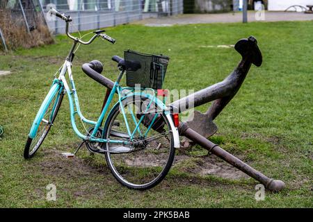 Bicicletta, bicicletta da donna, ben fissata con un lucchetto all'ancora di una nave di ferro, a Bremerhaven, Brema, Germania. Foto Stock