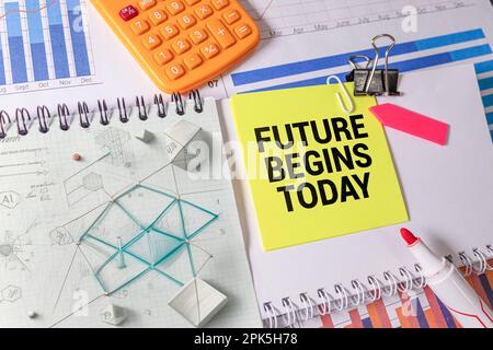 Il futuro inizia oggi blocco note sul blocco note rosso con la penna su concetto di business in legno background Foto Stock