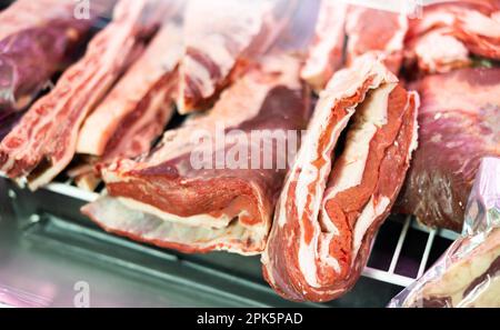 Pezzi di carne di manzo cruda giacenti al banco della macelleria Foto Stock