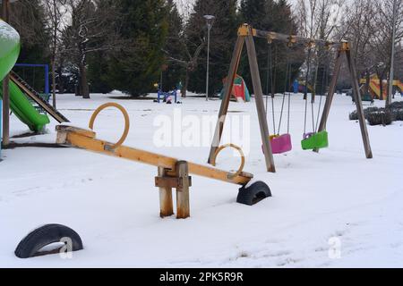 Parco giochi per bambini Teeter-Totter nel parco pubblico coperto di neve d'inverno Foto Stock