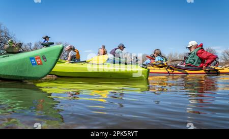 Evans, CO, USA - 1 aprile 2023: Un gruppo di kayakers sta riposando su un banco di sabbia dopo il portage della diga durante il viaggio primaverile in canoa sulla South Platte Rive Foto Stock