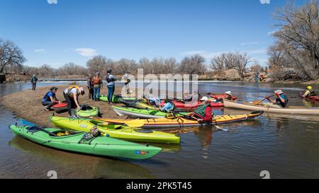 Evans, CO, USA - 1 aprile 2023: Un gruppo di kayakers sta riposando su un banco di sabbia dopo il portage della diga durante il viaggio primaverile in canoa sulla South Platte Rive Foto Stock