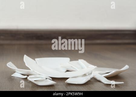 Pezzi di piastra in ceramica rotta su pavimenti in legno interni, spazio per il testo Foto Stock