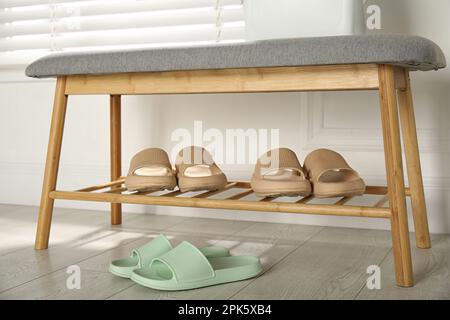 Eleganti ciabatte in gomma e panca con scarpe in camera Foto Stock