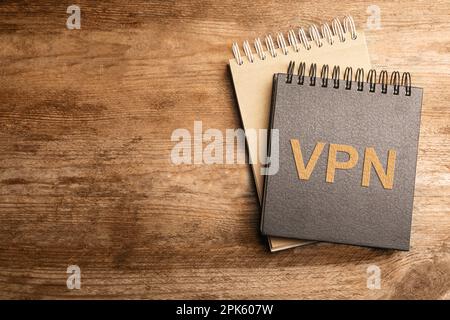 Notebook con acronimo VPN e spazio per testo su tavolo in legno, vista dall'alto. Connessione di rete protetta Foto Stock