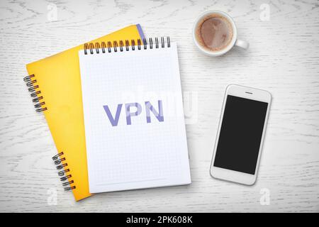 Notebook con acronimo VPN su tavolo di legno bianco, piatto. Connessione di rete protetta Foto Stock