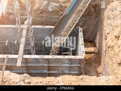 Versando cemento o calcestruzzo in casseforme di fondazione di nuovo edificio. Dettagli del cantiere Foto Stock