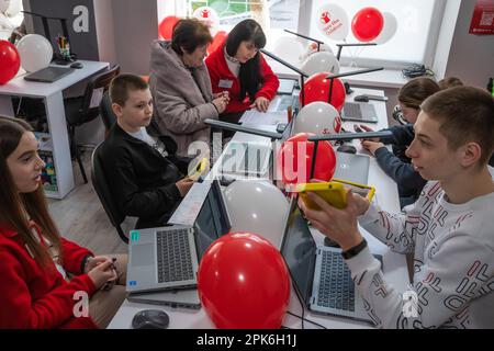 I bambini siedono a un tavolo con computer portatili e tablet in classe. Apertura ufficiale del Centro di apprendimento digitale nella Scuola superiore professionale di tecnologie informatiche e costruzione di Lviv, fondata dall'organizzazione umanitaria internazionale Save the Children con il sostegno del Ministero degli Affari Esteri norvegese. L'obiettivo del Digital Learning Center è un accesso sicuro all'apprendimento a distanza per i bambini dai 6 ai 17 anni, accesso all'istruzione interattiva non formale. Il centro di apprendimento digitale garantisce ai bambini un accesso continuo all'istruzione e alla socializzazione interna di Foto Stock