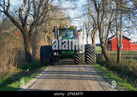 Trattore John Deere 9400 a due ruote, guida su strada piccola lungo il tragitto verso i campi, Uppland, Svezia Foto Stock