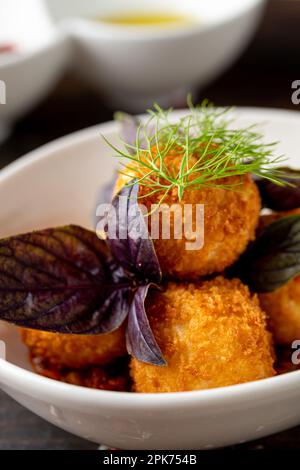 Arancini siciliani fritti fatti in casa ripieni di carne, con salsa di pomodoro Foto Stock