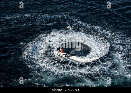 Un uomo (irriconoscibile) su una moto d'acqua gira un cerchio stretto sotto una nave da crociera a Cabo San Lucas, Messico Foto Stock