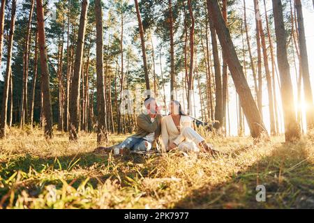 Felice coppia seduta a terra nella foresta Foto Stock