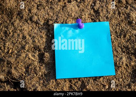 mappa viola pin di carta blu quadrato nota su fango marrone secco con spazio libero vuoto per il modello o area di copia vuota Foto Stock