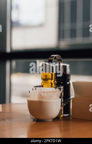 Tavolo servito per cena. Olio d'oliva, aceto e porta tovaglioli. Tavolo nel ristorante. Interno del caffè. Apparecchi per alimenti. Pepe e sale. Foto Stock