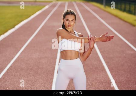 Concezione della cura del corpo. Giovane donna in abiti sportivi sta esercitandosi all'aperto Foto Stock