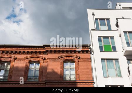 Nuovo edificio bianco di appartamenti vicino ad una casa di mattoni rossi Foto Stock