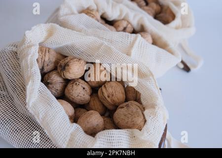 Noci sgusciate, mucchio di noci sgusciate in tre sacchetti di stoffa bianca su fondo bianco uno dopo l'altro. Sacchetti di stoffa pieni di noci sgusciate. Foto Stock