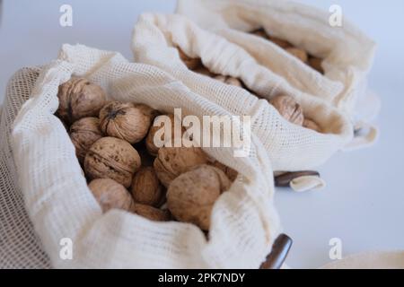 Noci sgusciate, mucchio di noci sgusciate in tre sacchetti di stoffa bianca su fondo bianco uno dopo l'altro. Sacchetti di stoffa pieni di noci sgusciate. Foto Stock