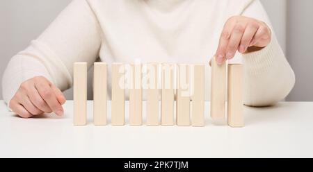 Blocchi di legno sul tavolo, la mano di una donna ne tiene uno. Il concetto di trovare dipendenti unici e di talento Foto Stock