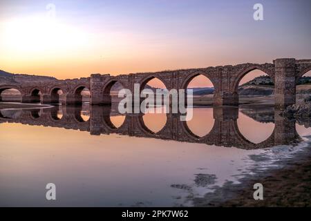 Ponte la Mesta di costruzione medievale sul fiume Guadiana all'alba nel bacino idrico di Cjara nella provincia di Badajoz, Spagna Foto Stock