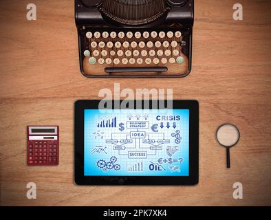 strategia aziendale su schermo tablet, macchina da scrivere vintage, lente di ingrandimento e calcolatrice su tavolo di legno Foto Stock