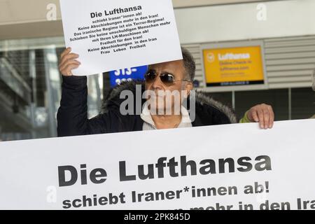 Francoforte, Germania. 06 aprile 2023. Un dimostratore tiene un cartello di fronte ai banchi Lufthansa durante una manifestazione all'aeroporto di Francoforte contro il coinvolgimento della compagnia aerea nei voli di deportazione per l'Iran, che recita: "Lufthansa sta deportando gli iraniani! Più recentemente, ci sono stati due voli con persone deportate in Iran. Foto: Sebastian Gollnow/dpa/Alamy Live News Foto Stock