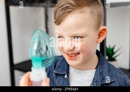 Il ragazzo carino mostra emozione dispiaciute prima di inalare. Foto Stock