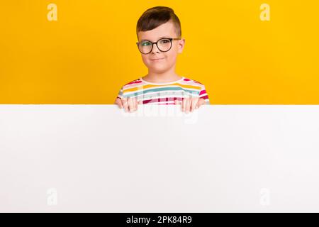 Foto di bell'uomo vestito a righe abiti alla moda stand dietro spazio vuoto presentando promo isolato su sfondo di colore giallo Foto Stock