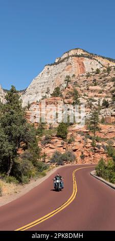 L'uomo senza casco guida la sua moto Harley Davidson sulla panoramica „Zion-Mount-Carmel-Highway“ passando davanti alle ripide montagne del Parco Nazionale di Zion orientale Foto Stock