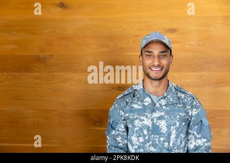 Ritratto di buon soldato maschio biraciale che indossa uniforme e cappuccio, guardando la macchina fotografica, con spazio copia. Stile di vita, servizio militare e tempo libero, unalte Foto Stock