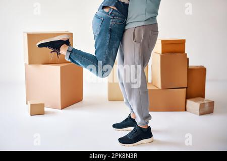Marito sollevare moglie circondata da scatole di cartone eccitato per muoversi in nuovo appartamento, coppia felice hanno divertimento abbracciando e festeggiando. Concetto di rilocazione Foto Stock
