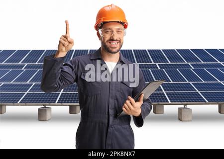 Lavoratore di fabbrica in piedi di fronte ai pannelli solari e puntando su isolato su sfondo bianco Foto Stock