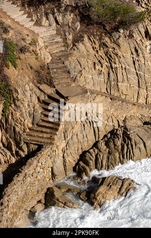 scale su una scogliera su una costa con onde forti Foto Stock