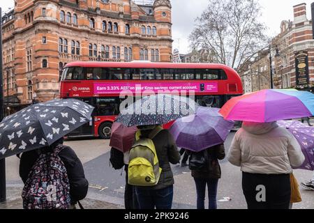 I turisti nel centro di Londra si rifugiano sotto gli ombrelloni davanti al Palace Theatre di Cambridge Circus, West End London, Inghilterra, Regno Unito Foto Stock