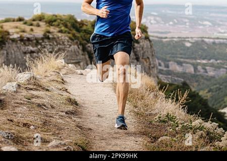 rangy runner maschio correre su sentiero di montagna, gambe muscolari uomo jogger atleta correre stretto percorso Foto Stock