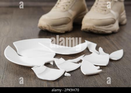 Donna in scarpe da ginnastica in piedi vicino a piastra rotta sul pavimento, primo piano Foto Stock