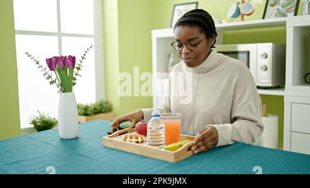 Donna afroamericana che fa colazione seduto sul tavolo nella sala da pranzo Foto Stock