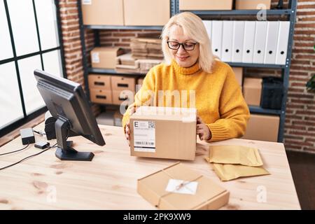 Donna bionda del Medio Evo ecommerce lavoratore di affari che tiene il pacchetto all'ufficio Foto Stock